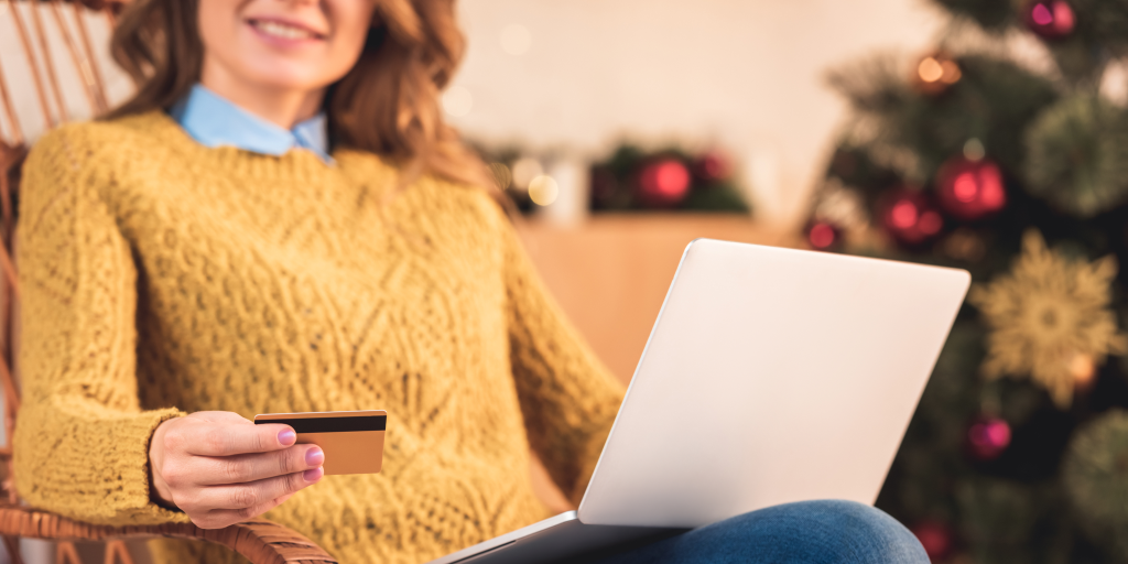 A woman sitting with a laptop and a payment card. 