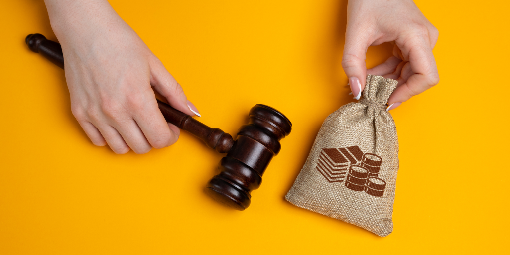 A gavel and a sack of coins on a yellow background. 