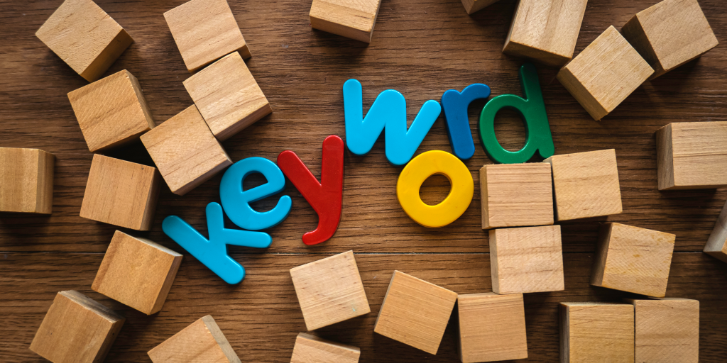 Letters spelling keyword surrounded by wooden cubes on a table. 