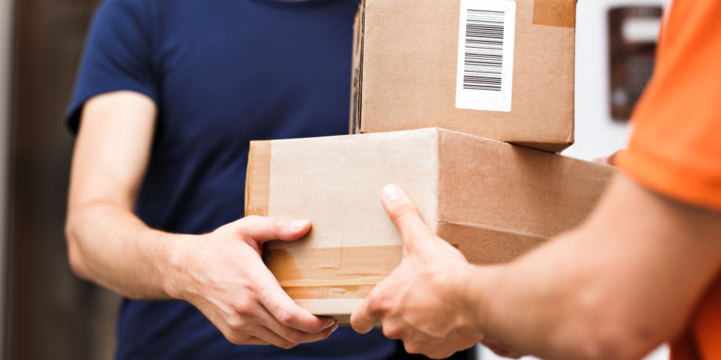 Two people exchanging packages. The packages are stacked on top of each other. 