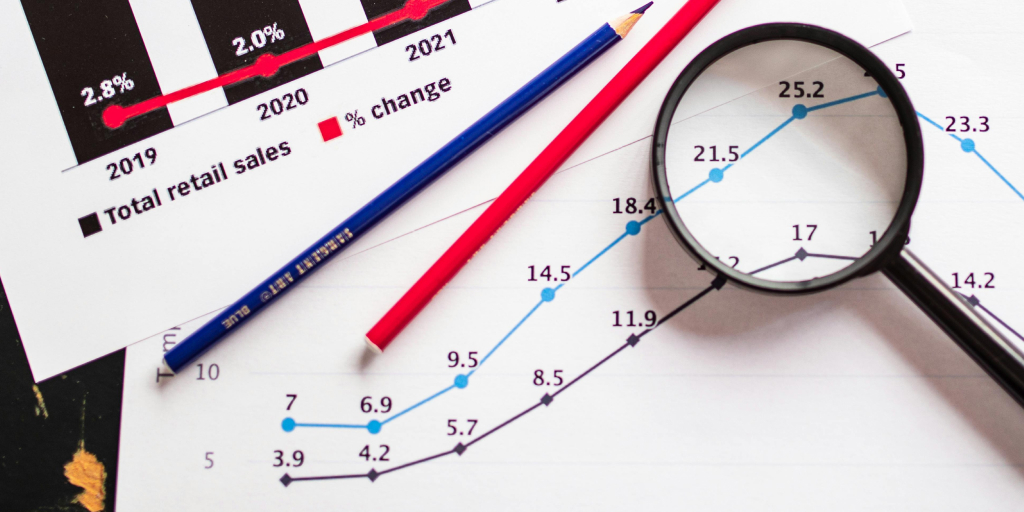 A growth graph, two pencil and magnifying glass spread across the surface of a table. 