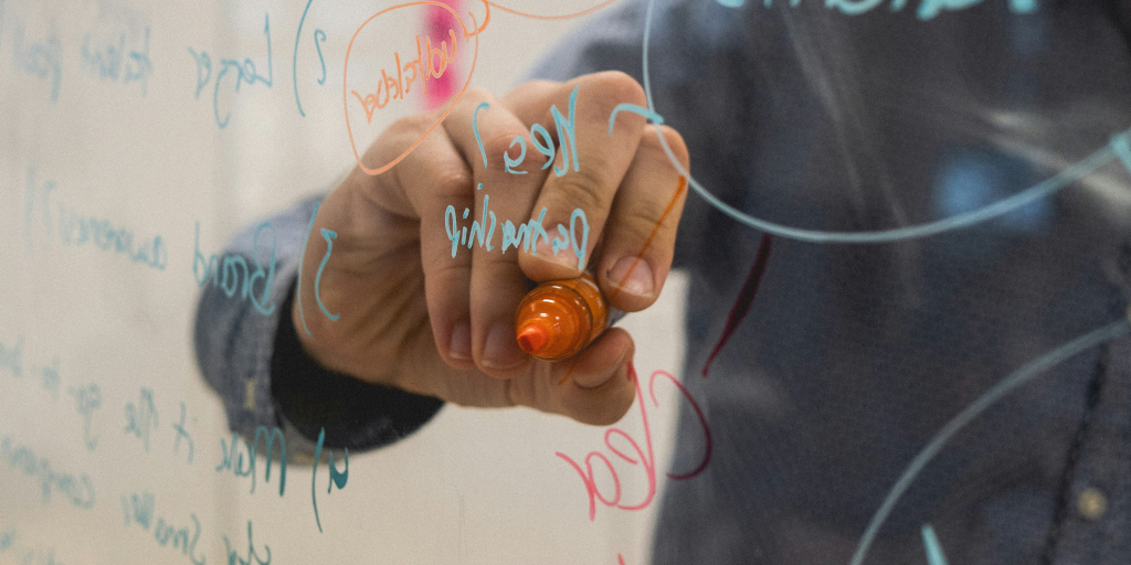 A person writing on a transparent surface with a marker. 