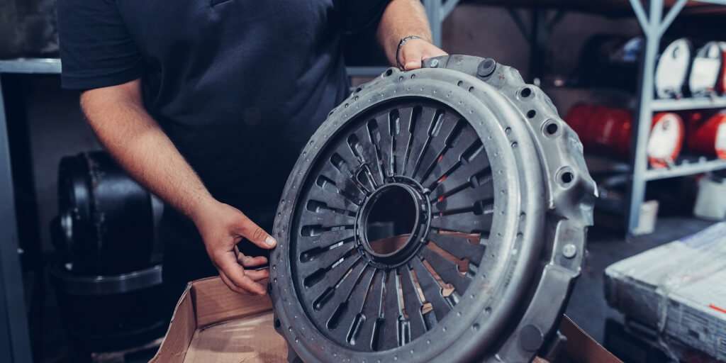 A man holding a car part in his hands.