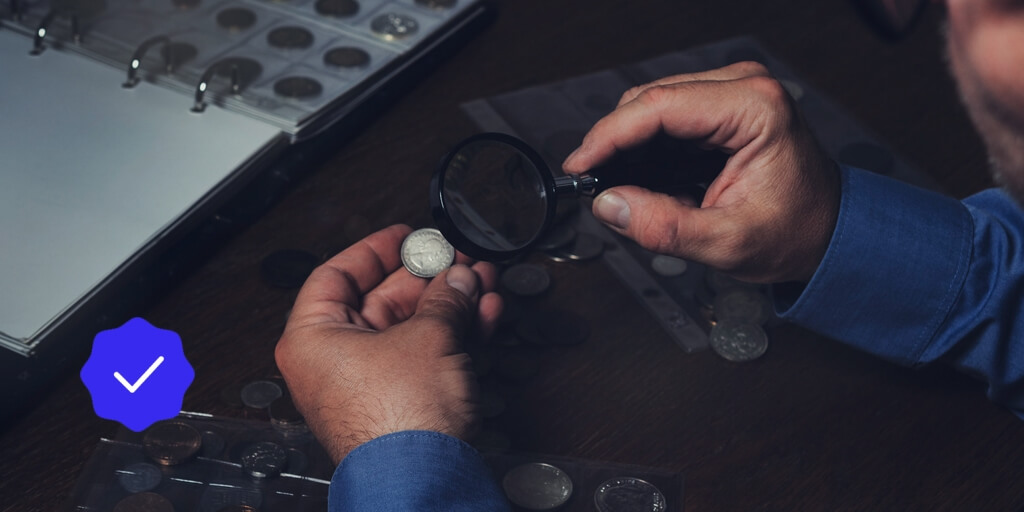 A man examining a coin under a magnifying glass.